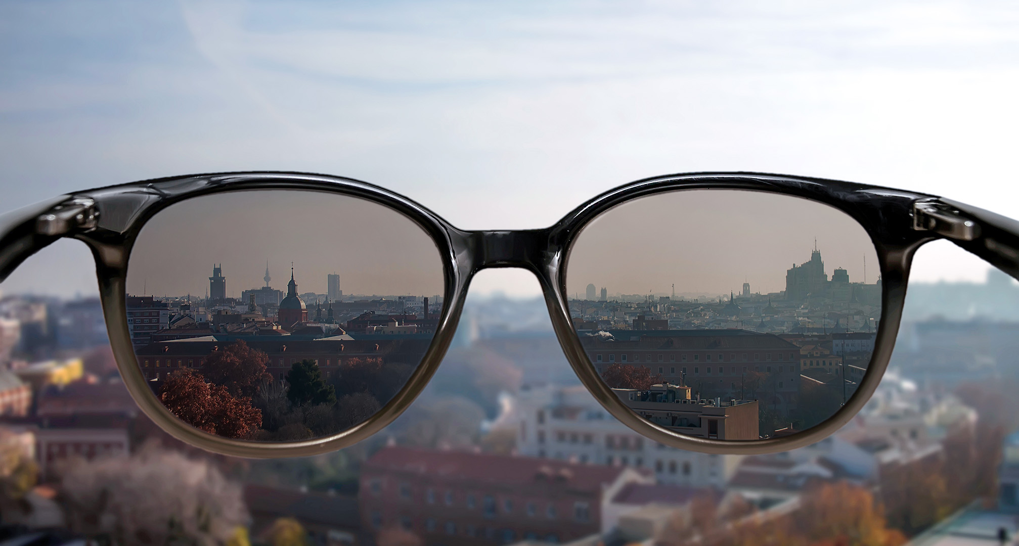 zonnebril gehouden voor stadsgezicht op achtergrond